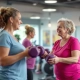 Vrouwvriendelijke fitnessruimte met hydraulische apparaten in cirkelopstelling waar twee 50+ vrouwen trainen onder begeleiding van een Curves-coach tijdens 30-minuten circuitprogramma.