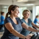 Vrouwen van boven de 50 trainen op hydraulische krachtapparatuur in cirkelopstelling bij Curves, begeleid door coach in ondersteunende en lichte fitnesszaal.