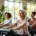 Diverse vrouwen trainen op Curves-apparatuur terwijl een coach correcte houding demonstreert in een lichte, rustgevende fitnessstudio met circuitopstelling.