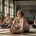 Diverse vrouwen doen ontspannende stretchoefeningen op yogamatten in een lichte Curves fitnessstudio, begeleid door een coach voor betere slaap.
