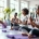 Diverse vrouwen doen stressreducerende oefeningen op paarse matten in een lichte Curves fitnessstudio met een coach en circuitapparatuur.