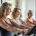 Vrouwen trainen op Curves-circuitapparatuur met behulpzame coach in lichte, moderne fitnessstudio. Ontspannen sfeer met focus op kracht en plezier.