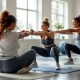 Diverse vrouwen voeren vloeroefeningen uit op paarse matten in een lichte Curves-sportschool, begeleid door een vriendelijke coach in een rustige sfeer.