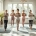 Diverse vrouwen doen rustige stretchoefeningen op paarse matten, begeleid door een Curves-coach in een warme fitnessstudio met hydraulische apparaten.