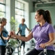 Diverse vrouwen trainen op hydraulische weerstandsmachines in een lichte, moderne fitnessstudio terwijl een coach begeleiding biedt in een uitnodigende, groene omgeving.