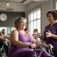 Vrouwen doen core-oefeningen met hydraulische apparatuur in lichte Curves fitnessruimte tijdens circuittraining sessie