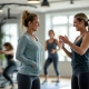 Senioren vrouwen trainen op hydraulische fitnessapparatuur in cirkelopstelling, begeleid door coach in vrouwvriendelijke ruimte met zachte verlichting en motiverende sfeer.