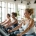 Diverse vrouwen trainen op hydraulische apparaten in een licht vrouwelijke fitnesscentrum met een coach die persoonlijke begeleiding biedt.