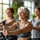 Diverse vrouwen van 40-50 jaar trainen vol zelfvertrouwen op hydraulische apparatuur in een licht fitnesscentrum voor vrouwen, begeleid door een coach.