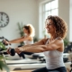 Vrouwen trainen op hydraulische machines in een lichte fitnessstudio voor vrouwen, met coach begeleiding tijdens een 30-minuten circuit.