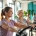 Vrouwen van verschillende leeftijden trainen op hydraulische apparatuur in een lichte Curves sportschool met behulpzame coach.