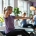 Twee vrouwen trainen op hydraulische fitnessapparatuur in een lichte, uitnodigende sportschool voor vrouwen, begeleid door een coach in een warme, ondersteunende omgeving.