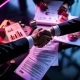 Zakelijke handdruk boven moderne vergadertafel met franchise documenten, munten en gebouwmodellen in paars licht