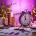 Moderne stopwatch omringd door miniatuur gebouwen, sleutels en documenten in paarse Curves franchise-kleuren op bureau
