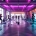 Vrouwen trainen in moderne fitnessstudio met paarse en turquoise verlichting en hydraulische fitnessapparatuur
