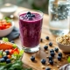 Houten tafel met post-workout voeding: proteïne smoothie, zalm, quinoa salade, Griekse yoghurt en water fles