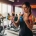 Vastberaden vrouw van middelbare leeftijd traint met kleurrijke dumbbells in heldere fitnessstudio met andere vrouwen op achtergrond