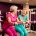 Twee vrouwen van middelbare leeftijd lachen samen op hydraulische fitnessapparaten in een paarse damesfitnessclub.