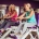Twee vrouwen lachen samen tijdens een training op hydraulische fitnessapparaten in een vrouwenfitnessclub met paarse muren.
